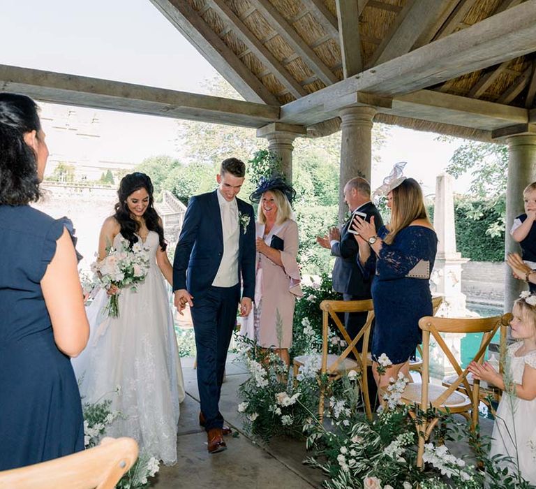 Bride & groom hold hands as they walk together on their wedding day