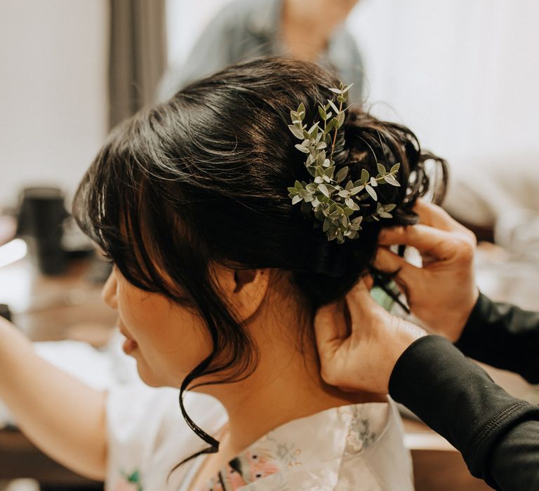 Bride with curled wedding up do has foliage hair decorations pinned 