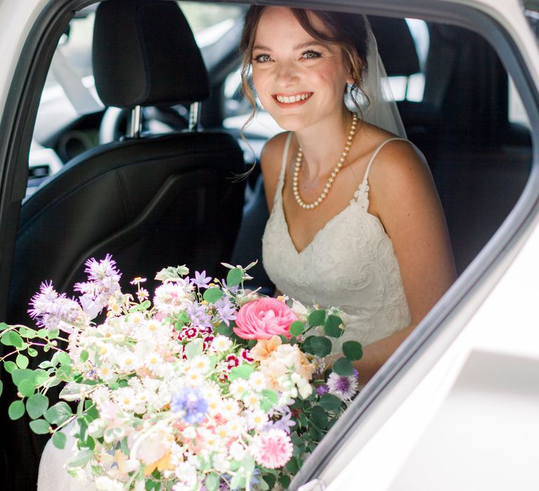 Bride in classic pearl necklace and v-neck lace wedding gown with bright and bold bouquet