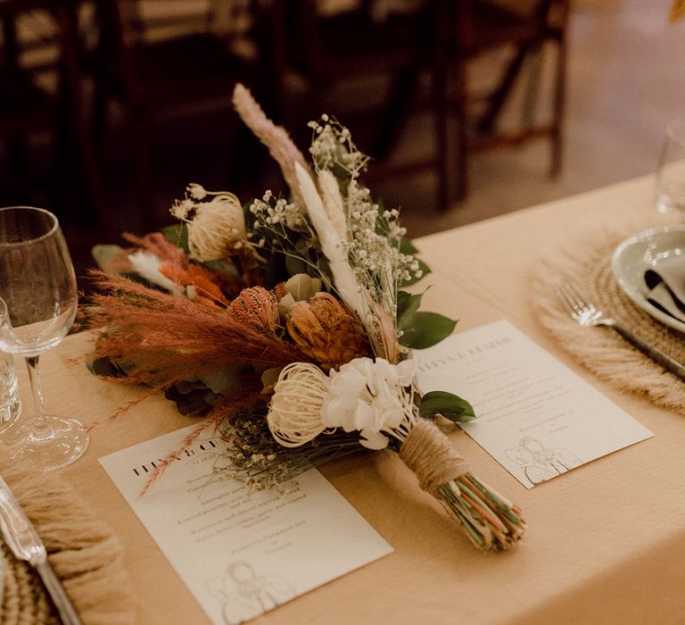 Wedding stationery personalised menu with sketch and dried flower bouquet on top table for the bride and groom