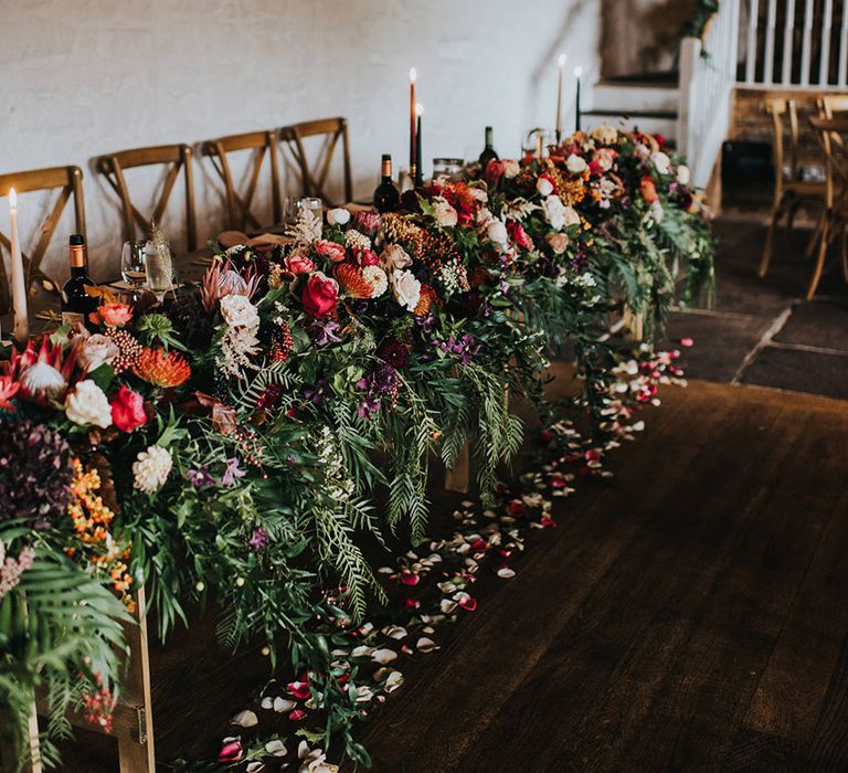 Top table wedding flowers with green foliage, red roses and pink carnations 