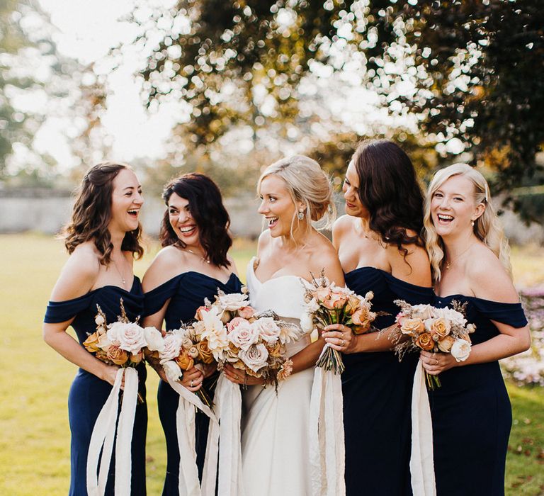 Smiling bride and bridesmaids at Elmore cost wedding in navy blue bridesmaid dresses