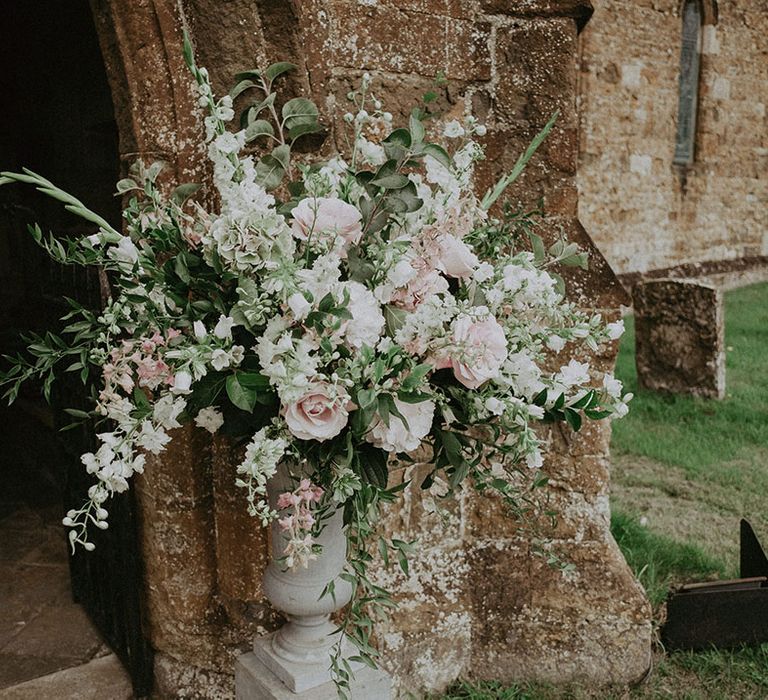 Pink rose and lush greenery wedding flowers outside of church wedding venue