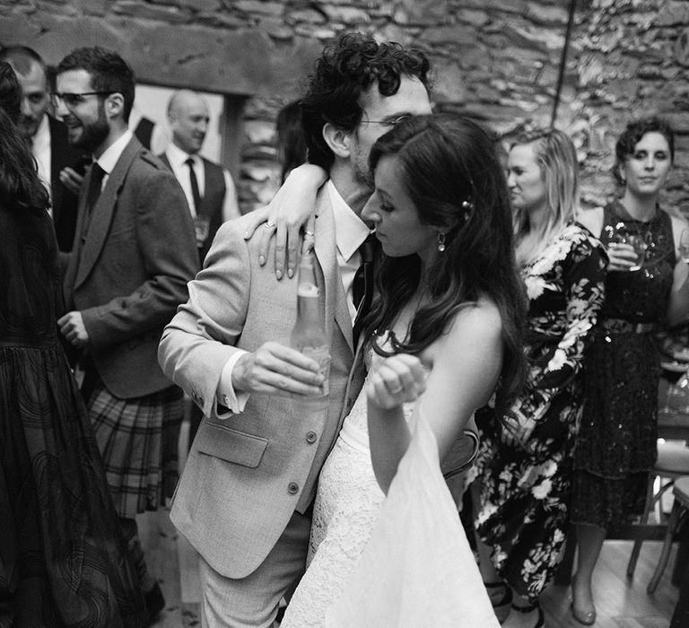 Bride and groom dance together with their wedding guests at wedding reception 