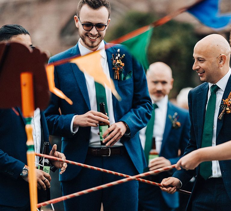 Bride in off the shoulder dress with groom in blue checkered suit with groomsman in blue suit with autumnal buttonhole 