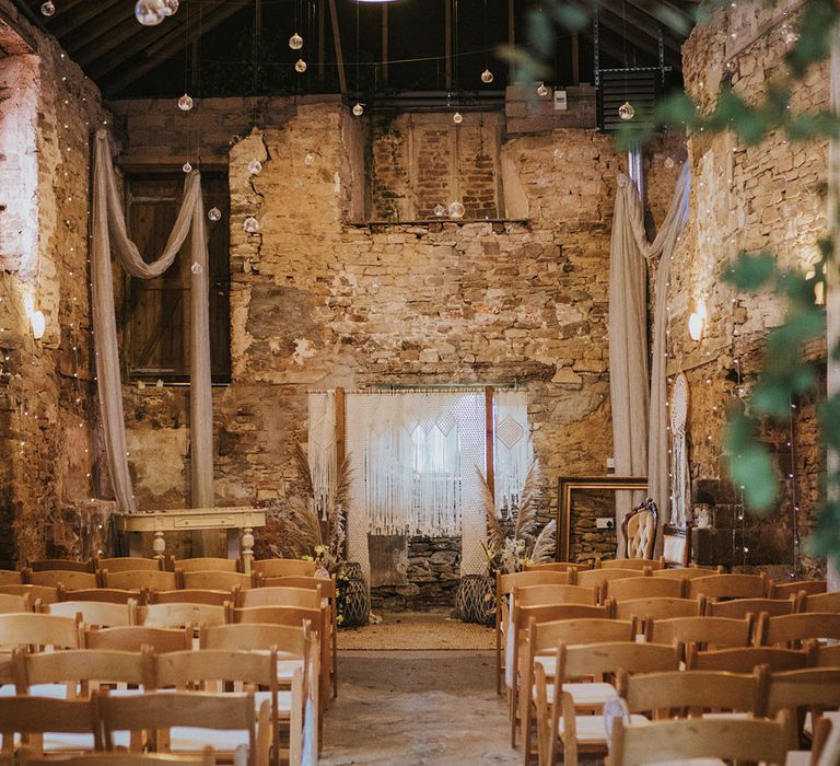 Rustic and boho styled wedding venue ceremony room with macrame decor, fairy lights and dried flowers 