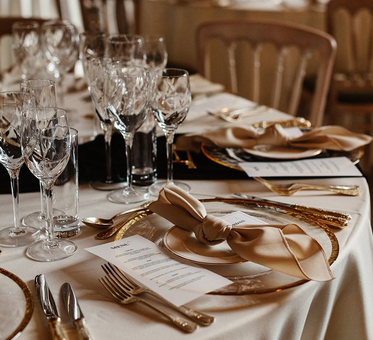 Gold cutlery and plating with white tablecloth and black candles for autumn witchy style wedding at Drumtochty Castle