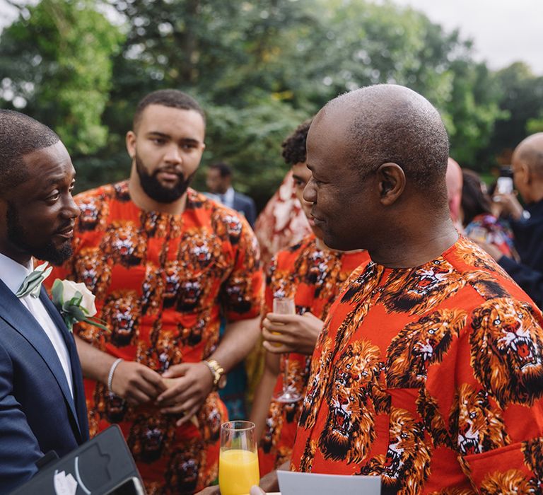 Groom speaks to wedding guests in orange lion print outfits 