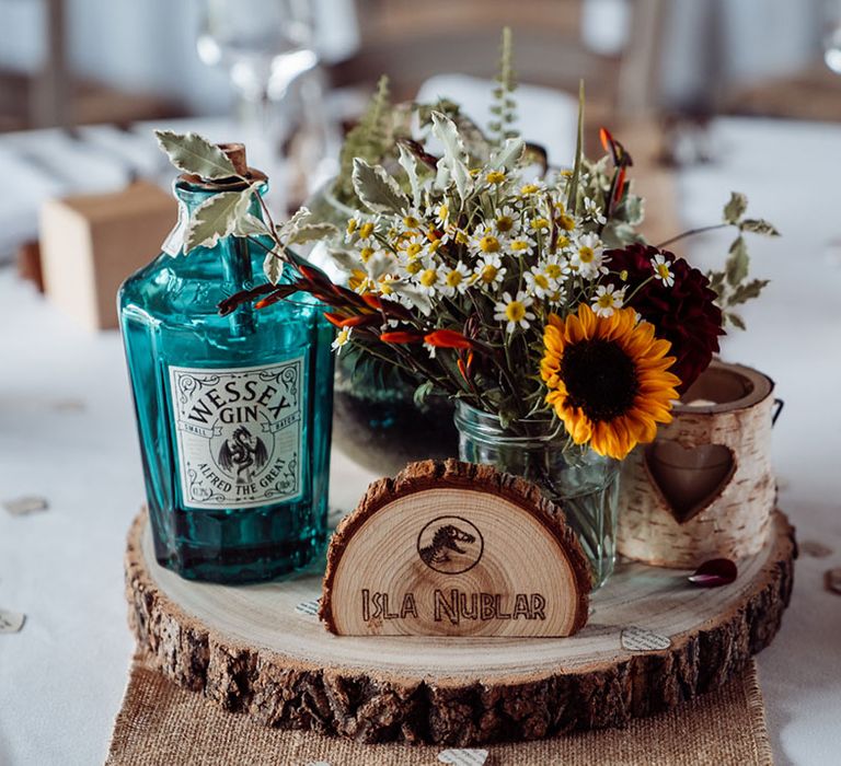 wood slice table centrepiece decor with engraved names of places in fictional worlds that the couple are fans of like Jurassic Park 