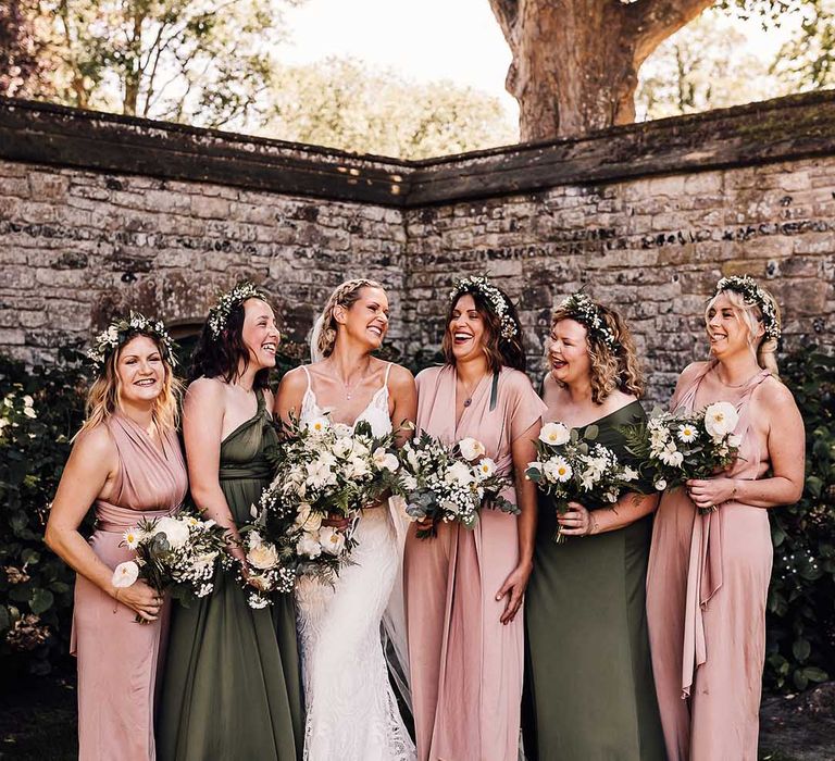 Bride with braided updo with bridesmaids in pink and green dresses with white flower bouquets 