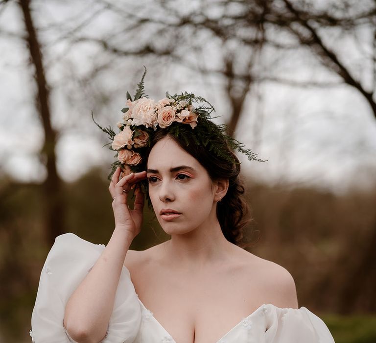 Bride in a strapless wedding dress with plunging neckline and puff sleeves wearing a pink flower crown 