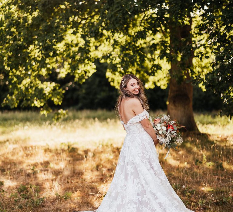 Bride in boho lace off the shoulder wedding gown with long train and a intricate hair piece 