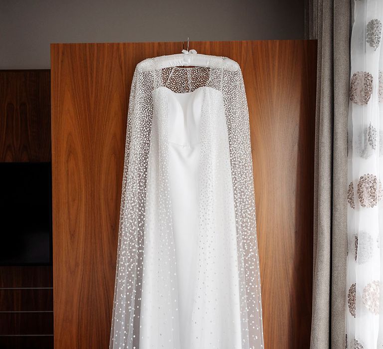 Jesus Peiro wedding cape with glitter polka dots hangs across Suzanne Neville wedding dress