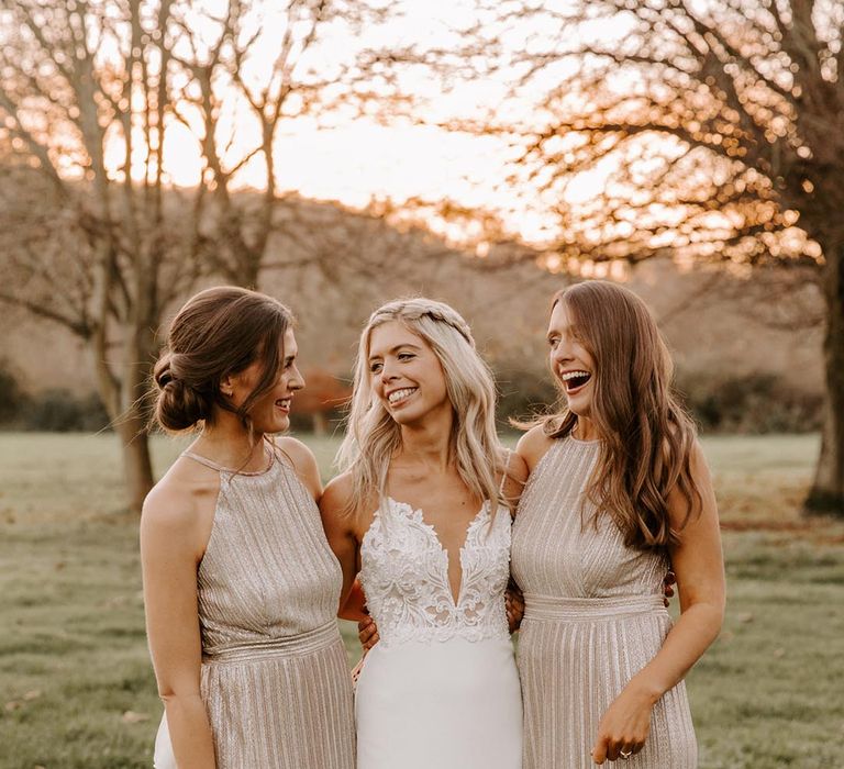 Bridesmaid in shiny gold metallic dresses with the bride during golden hour