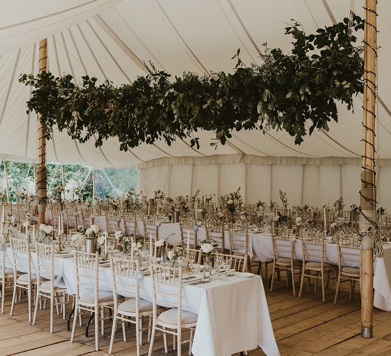 White marquee decorated with foliage with pretty white tablescapes 