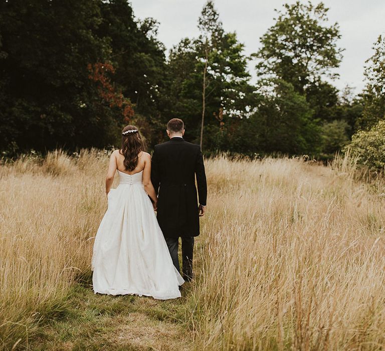 Bride and groom walk holding hands 