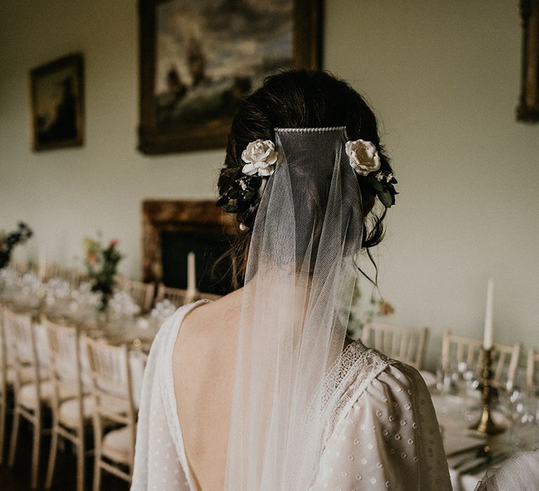 Bride in open back wedding dress with batwing sleeves, white rose hair clips and sheer veil attached by hair slide