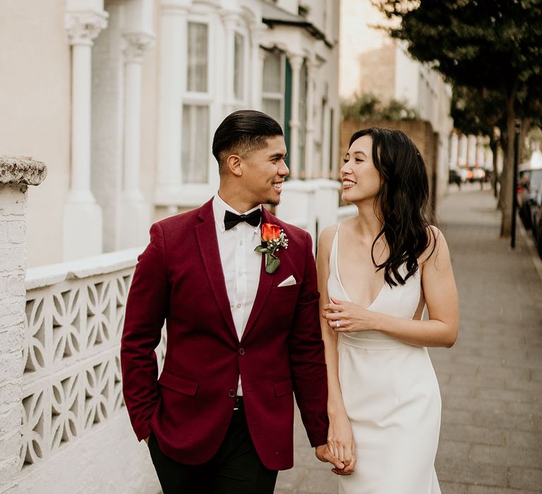 Groom in a magenta suit walking with the bride for their London wedding 