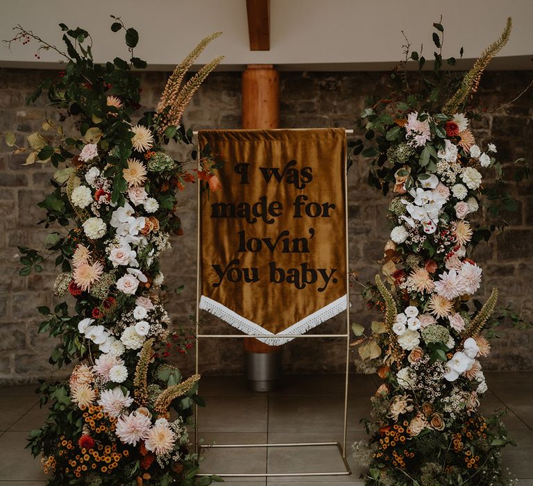 Dark burnt orange backdrop banner with white fringing and I Was Made For Loving' You Baby written in dark brown 70's inspired font 