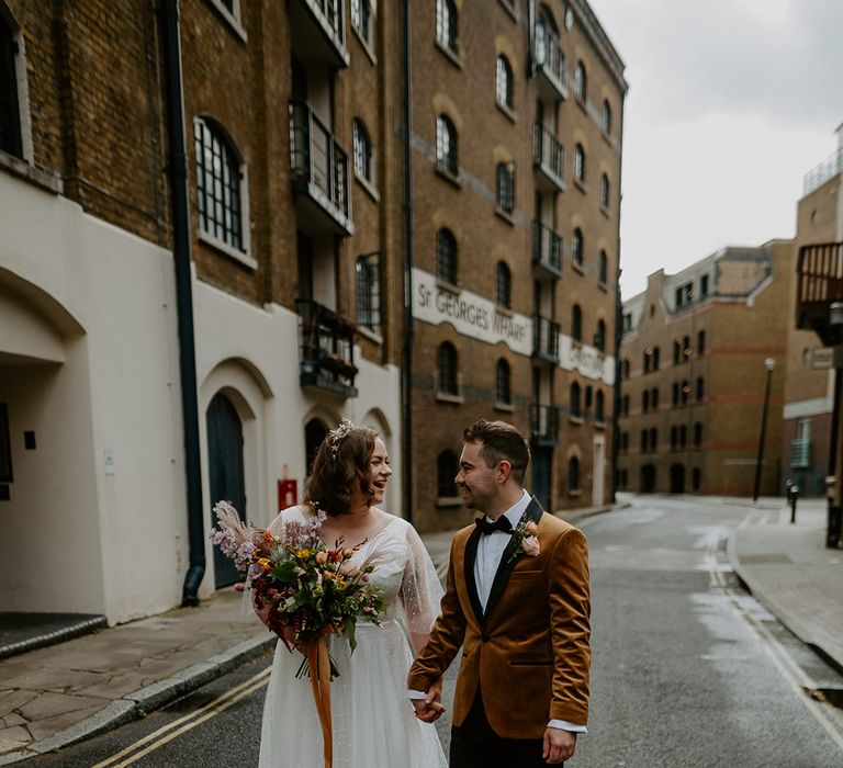 Bride and Groom hold hands and walk through the streets at London Wedding