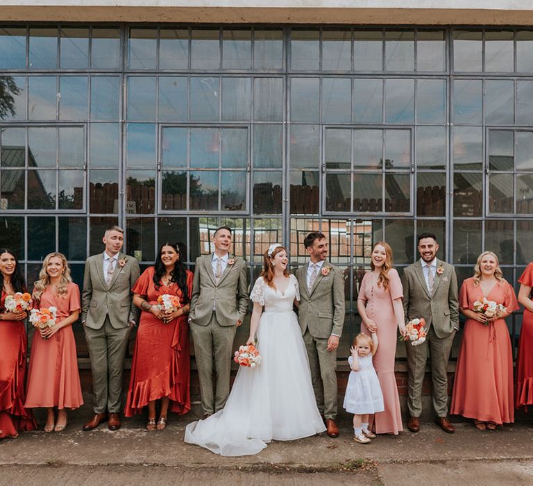 The groomsmen pose with the, flower girl, bridesmaids and the bride and groom for a wedding party shot 