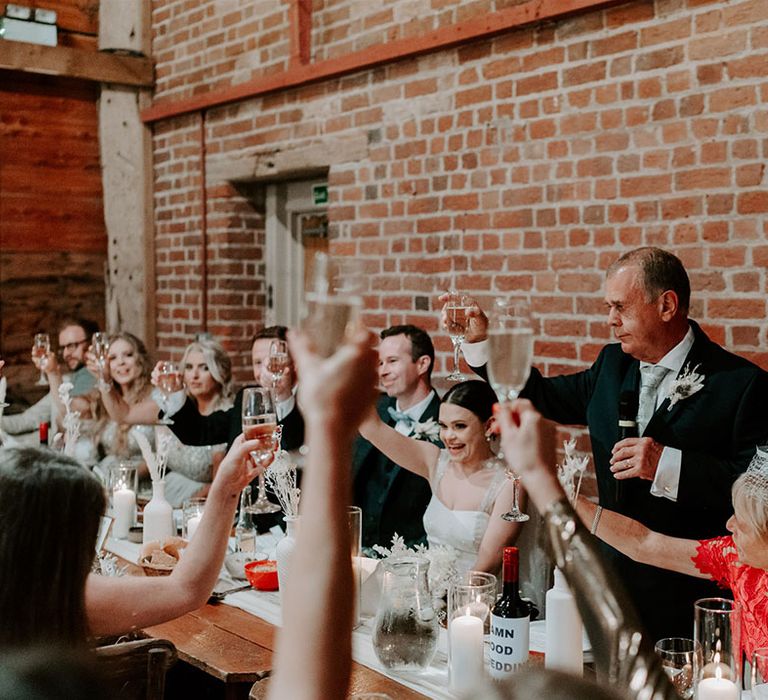 Father of the bride makes a toast and everyone raises their glasses for the bride and groom 