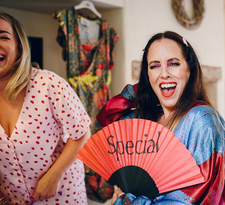 Bride in light blue and red satin robe with red and black paper fan with "special" written on it