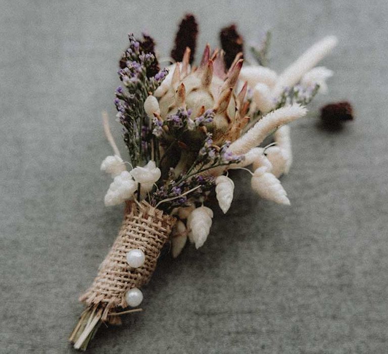 DIY wildflower buttonhole tied with brown hessian ribbon and pinned with pearl pin