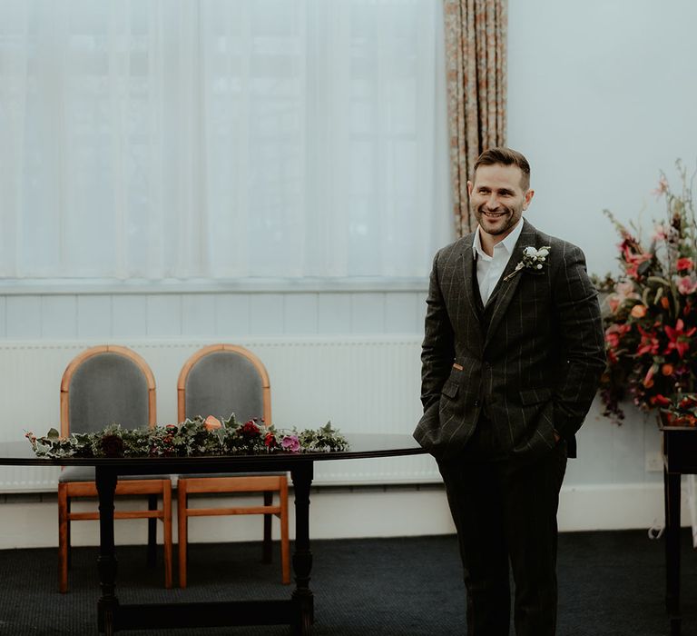 Groom in dark grey suit stands at the altar waiting for the bride for the registry office civil ceremony 