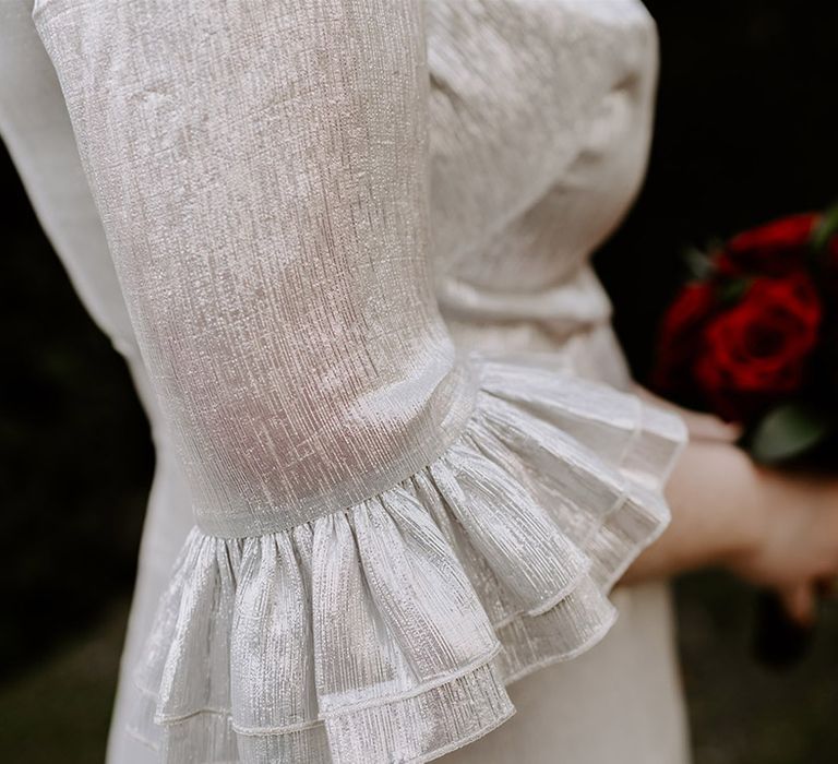 Close up of the bride's The Vamprire's Wife silver metallic wedding dress with ruffle sleeve detail 