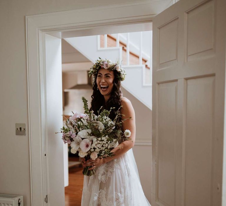 Bride doing first look for bridesmaids wearing ethereal, celestial 3d appliqué sheer overlay wedding dress and bridal flower crown holding large white rose, peony, dried flower and foliage bridal bouquet 