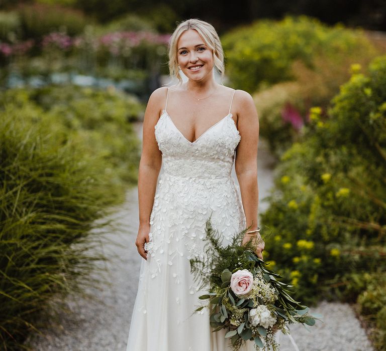 Bride in spaghetti strap floral applique wedding dress holding pink and white rose wedding bouquet 