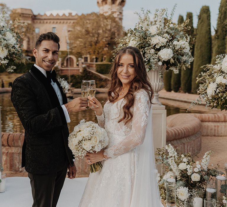 Bride and groom sharing a glass of champagne with white carnation, eucalyptus and dried flower decorations surrounding them