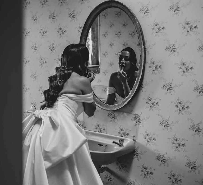 bride looking in the mirror in a strapless wedding dress with bow back detail 