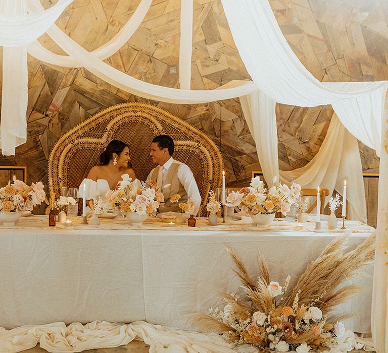 double peacock chair at the top table with hanging drape decor and muted colour flowers 