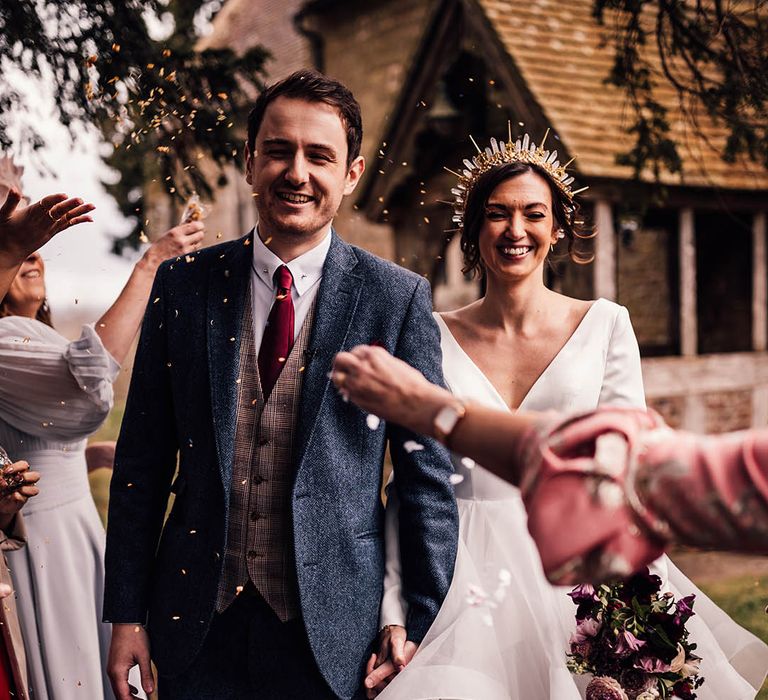 Groom in twee navy suit with checkered waistcoat with dark red tie with bride in gold crystal crown in layered wedding stationery