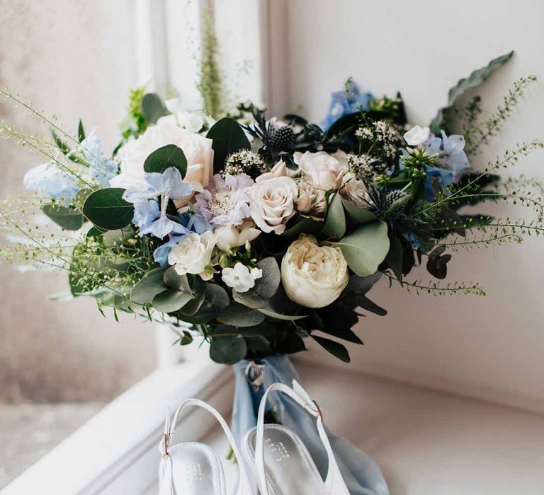 Eucalyptus, foliage, garden rose, gardenia, bluebell and dried flower bridal bouquet tied with dusky blue ribbon 