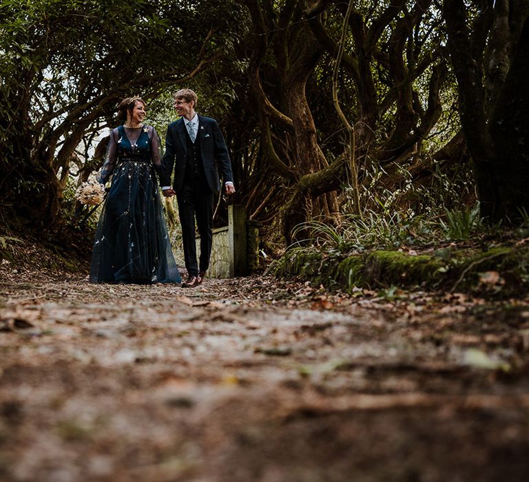 The bride and groom walk around their woodland wedding venue together 