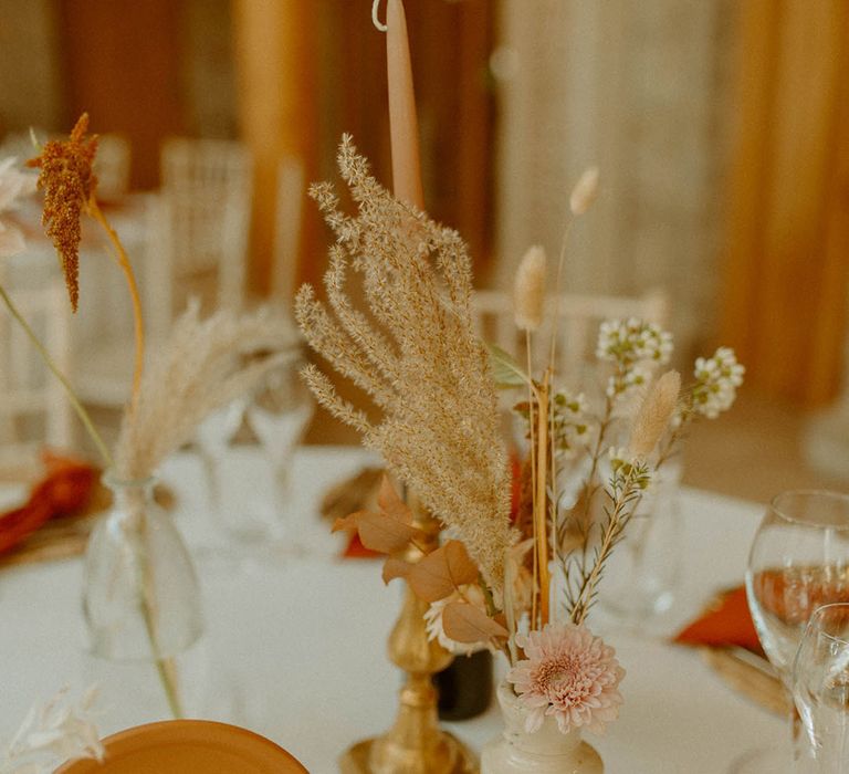 Table number sign on terracotta plate with taper candles and flower arrangement with bunny grass 