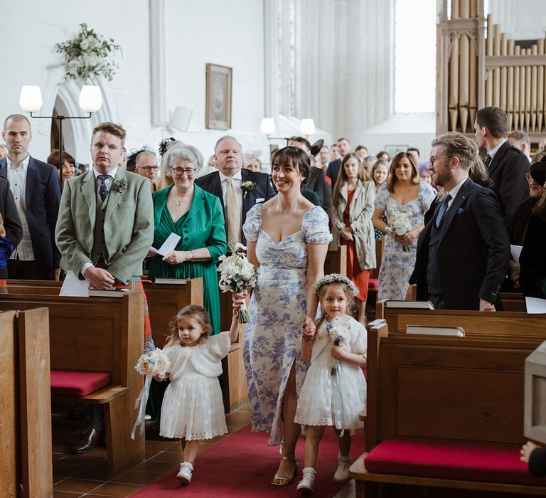 Flower girls and bridesmaids walking down the aisle at church wedding 