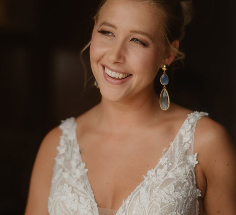 Bride in appliqué deep v wedding dress with straps wearing droplet earrings 