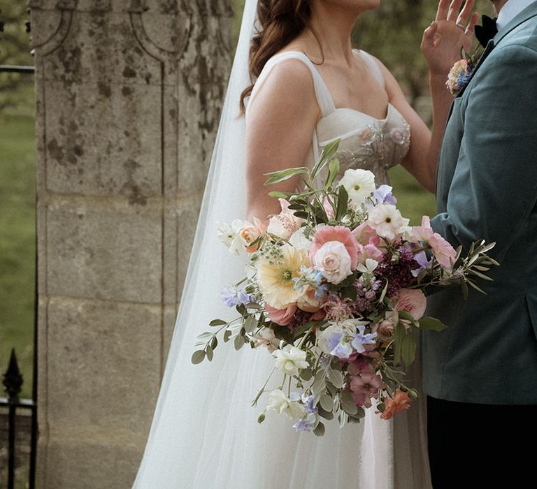 Bride holding pastel yellow, pink, and purple wedding bouquet 