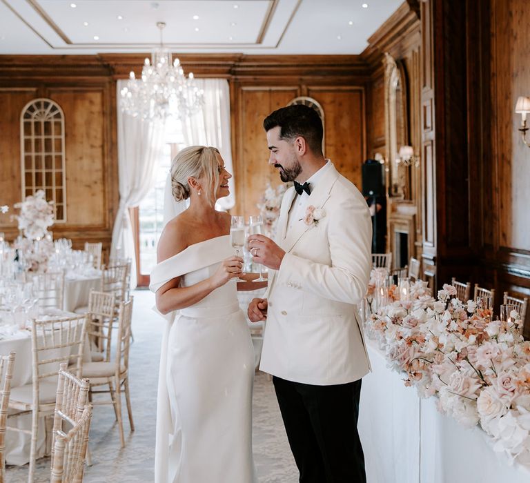 Groom in white suit jacket with bride at their wedding breakfast at Hedsor House 