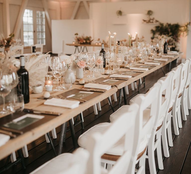 wedding table decorations at tenuta il cigno wedding with pink flower stems in vases, black place mats and white chairs 