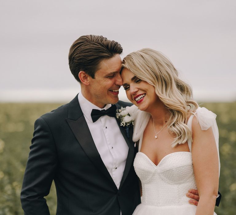 Bride in corset bodice princess wedding dress by Eva Lendel with the groom in a black tuxedo 