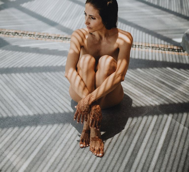 Bride sits down with traditional henna tattoos on her hands and feet