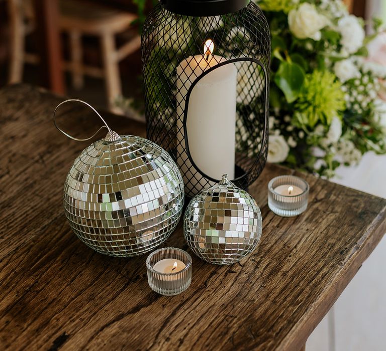 Disco balls and candles in black lanterns decorate the wedding venue 