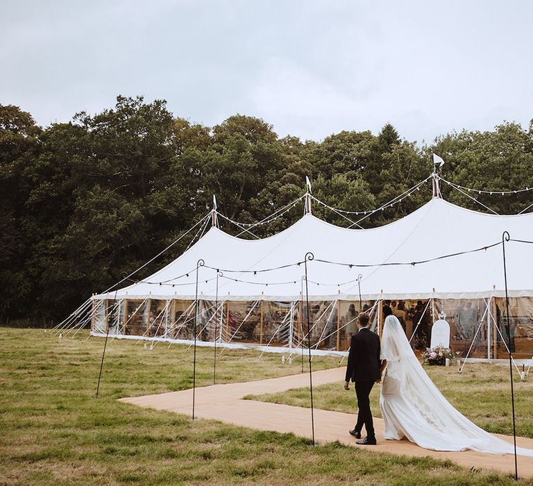 Bride and groom walking on the way to their marquee reception in Lincolnshire 