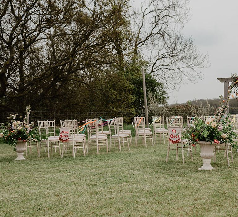 Outdoor wedding ceremony at Hardwick Moat Weddings with banner signs and colourful flowers 