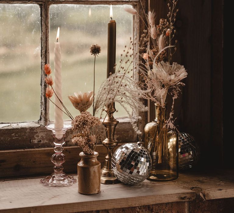 Mismatched vintage wedding decor with candles and disco balls with dried wedding flowers 